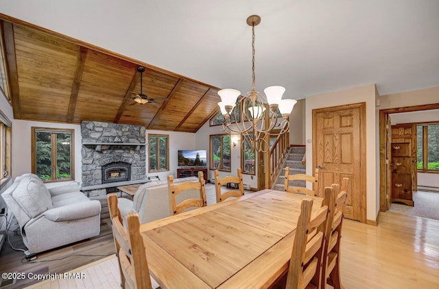 dining area featuring vaulted ceiling with beams, a stone fireplace, plenty of natural light, and wooden ceiling