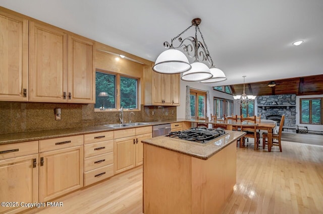 kitchen featuring light brown cabinetry, sink, decorative light fixtures, a center island, and appliances with stainless steel finishes