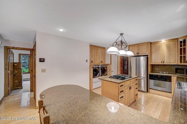 kitchen featuring pendant lighting, stainless steel appliances, a center island, light hardwood / wood-style floors, and separate washer and dryer