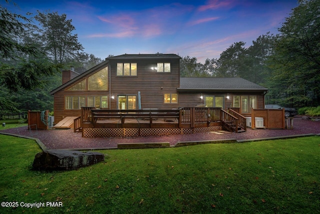 back house at dusk featuring a yard and a deck