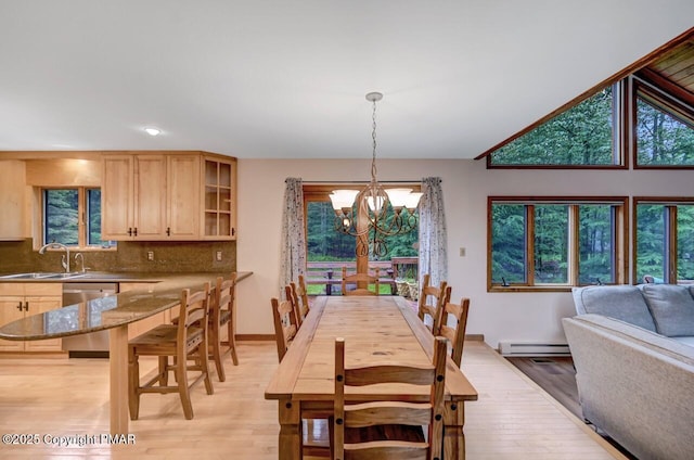 dining space featuring sink, baseboard heating, an inviting chandelier, plenty of natural light, and light hardwood / wood-style floors