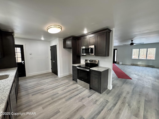 kitchen with light stone countertops, light wood-style flooring, a baseboard heating unit, and stainless steel appliances