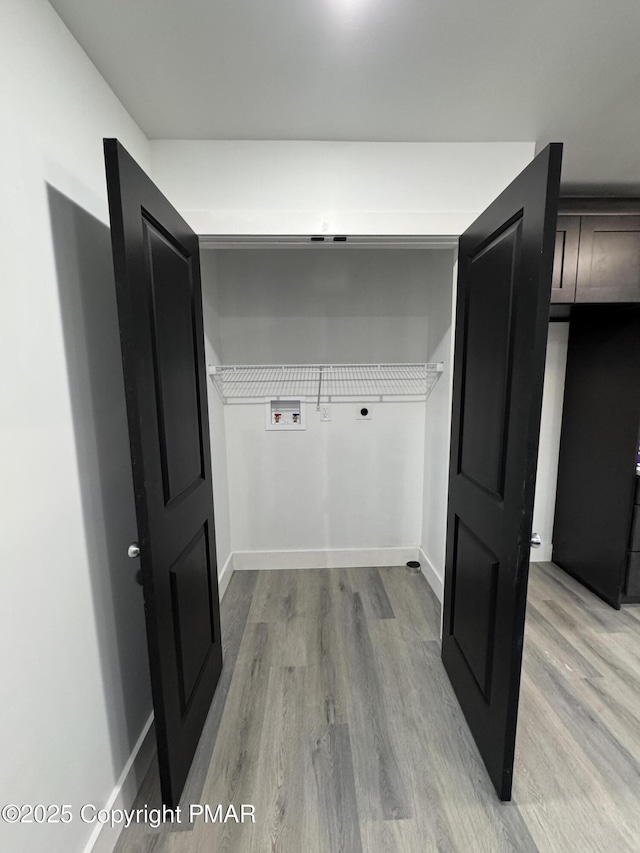 clothes washing area featuring laundry area, light wood-style flooring, washer hookup, and baseboards