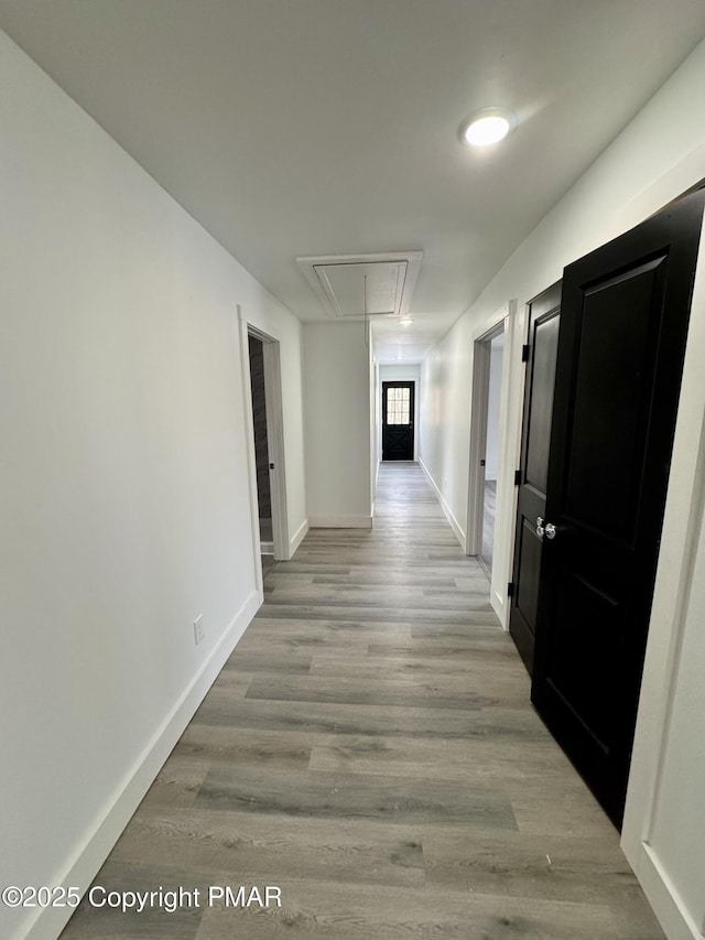 hall featuring attic access, baseboards, and wood finished floors