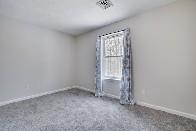 carpeted empty room featuring visible vents, a textured ceiling, and baseboards