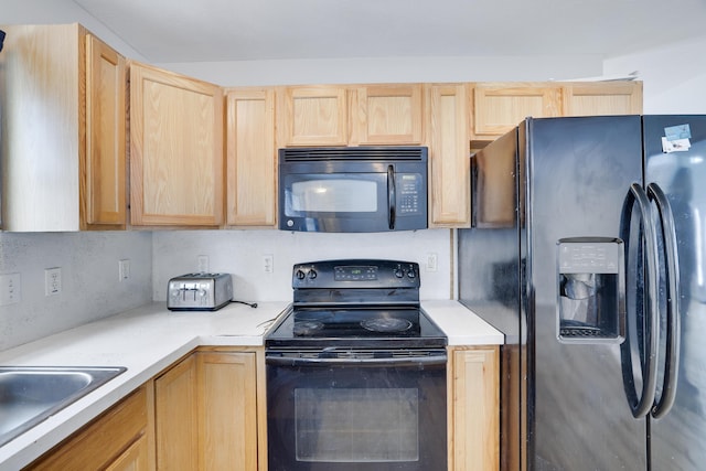 kitchen featuring light countertops, light brown cabinets, a sink, and black appliances