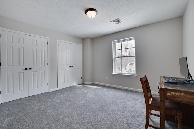 carpeted office with visible vents, a textured ceiling, and baseboards