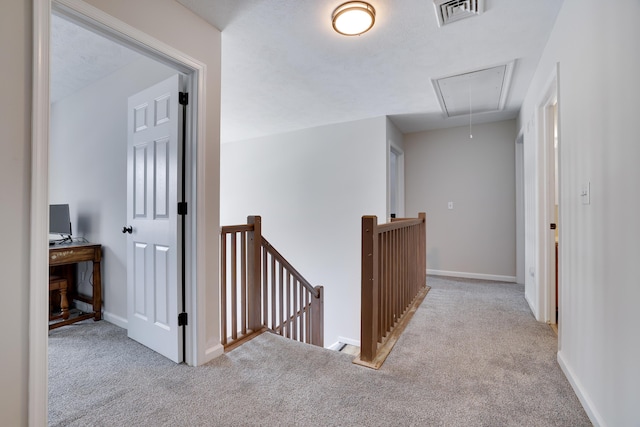 corridor with carpet, attic access, visible vents, and an upstairs landing