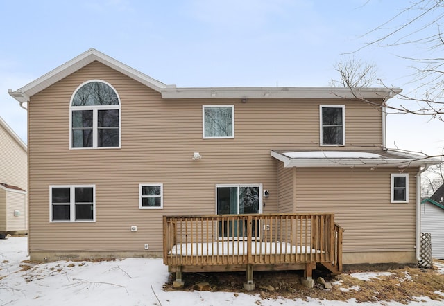 snow covered rear of property with a deck