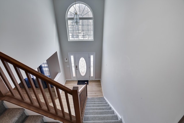 foyer entrance with baseboards, stairway, a high ceiling, and wood finished floors