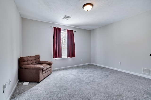 unfurnished room with a textured ceiling, visible vents, and carpet flooring