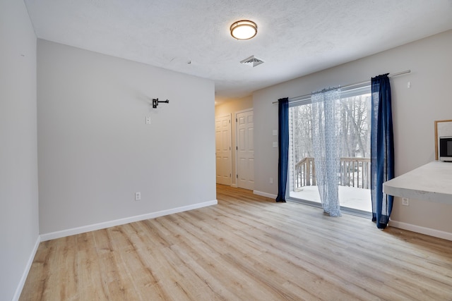 interior space featuring baseboards, a textured ceiling, visible vents, and wood finished floors