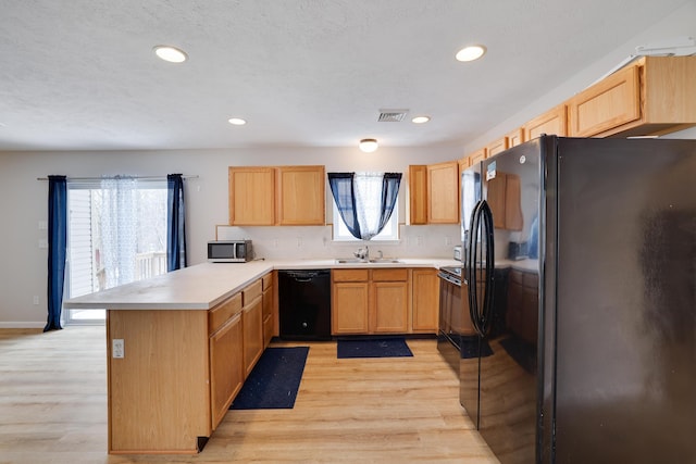 kitchen with visible vents, light wood-style flooring, a sink, a peninsula, and black appliances