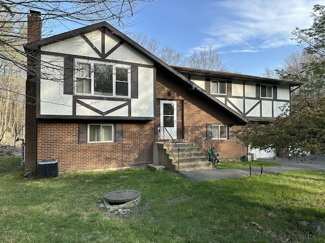 1010 Knollwood Dr, Tobyhanna, PA 18466 - rear view of house featuring brick siding, cooling unit, a chimney, a yard, and stucco siding