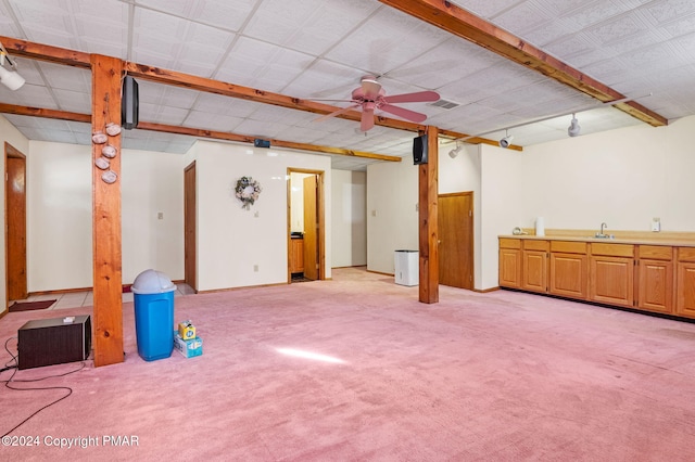 finished below grade area with light colored carpet, visible vents, ceiling fan, wet bar, and baseboards