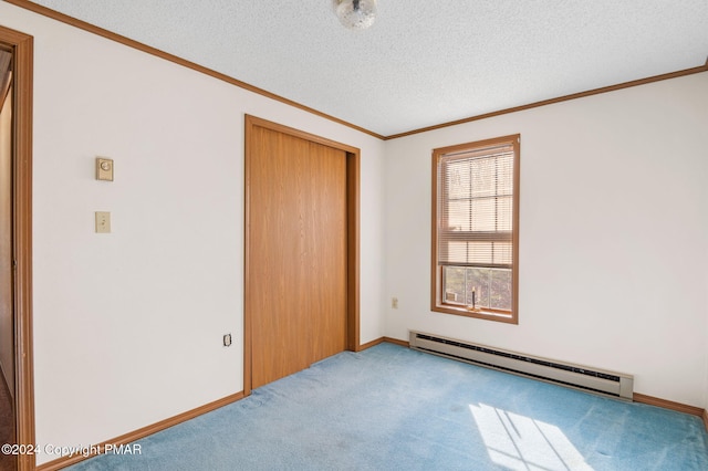 empty room with baseboards, crown molding, a textured ceiling, carpet flooring, and a baseboard heating unit