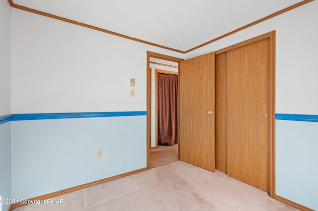 unfurnished bedroom with ornamental molding, carpet, and a closet