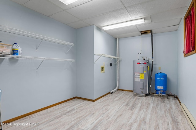 utility room featuring water heater and a baseboard heating unit