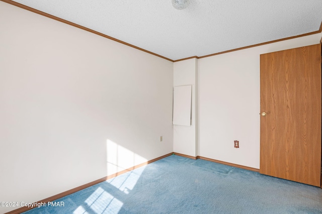 carpeted spare room with a textured ceiling, baseboards, and crown molding