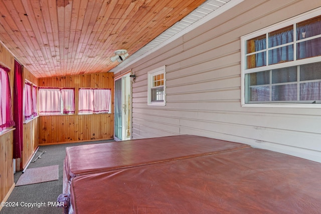 unfurnished bedroom featuring carpet floors, wooden ceiling, and wood walls