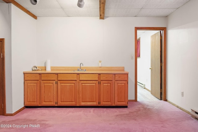 kitchen with light countertops, baseboard heating, light carpet, a sink, and baseboards