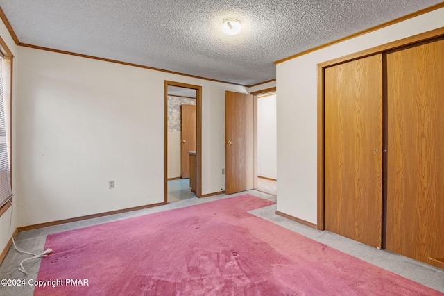 unfurnished bedroom featuring a textured ceiling, baseboards, a closet, carpet, and crown molding