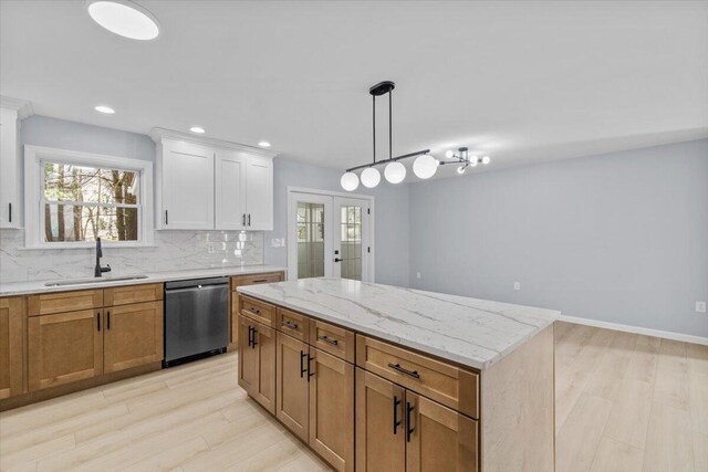 kitchen with stainless steel dishwasher, decorative backsplash, a sink, and light wood-style flooring