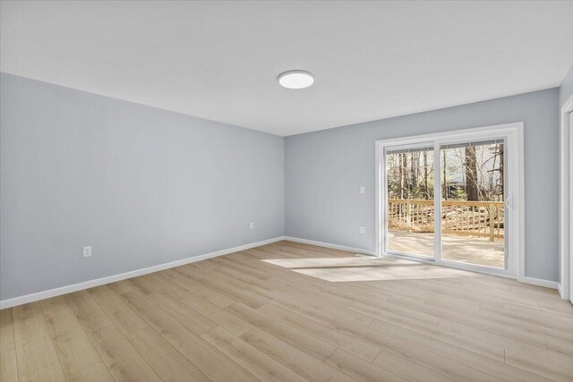 spare room featuring baseboards and light wood finished floors