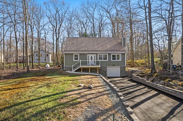 view of front facade featuring a chimney, metal roof, dirt driveway, an attached garage, and stone siding