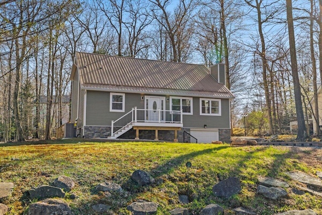 rear view of property featuring a chimney, metal roof, a yard, an attached garage, and stairs