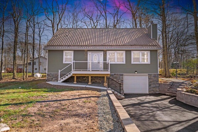 exterior space featuring aphalt driveway, stone siding, a chimney, and metal roof