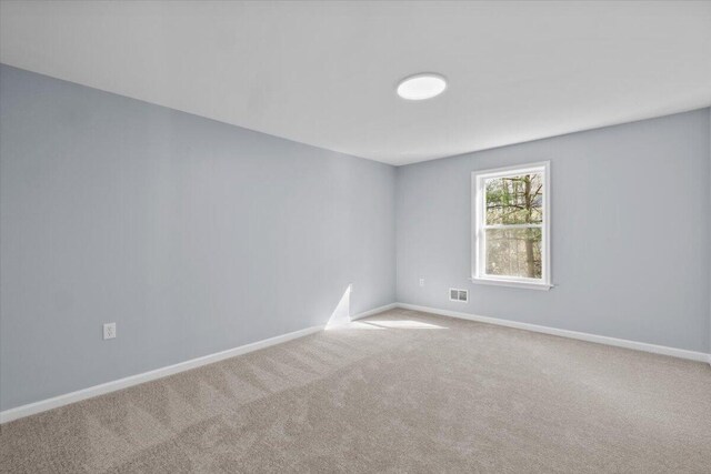 empty room featuring visible vents, carpet, and baseboards