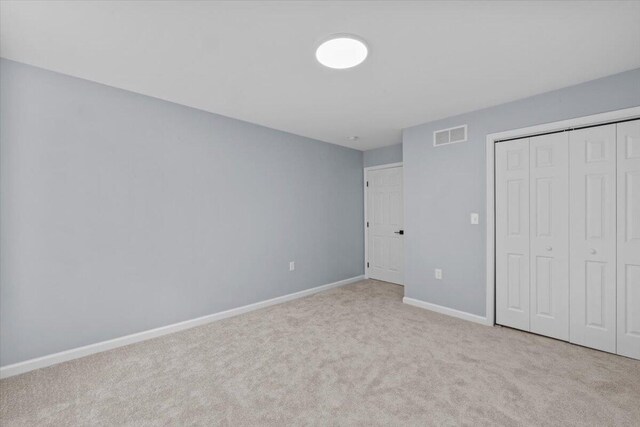 unfurnished bedroom featuring carpet floors, baseboards, visible vents, and a closet