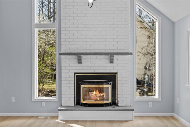 room details featuring baseboards, a brick fireplace, wood finished floors, and visible vents