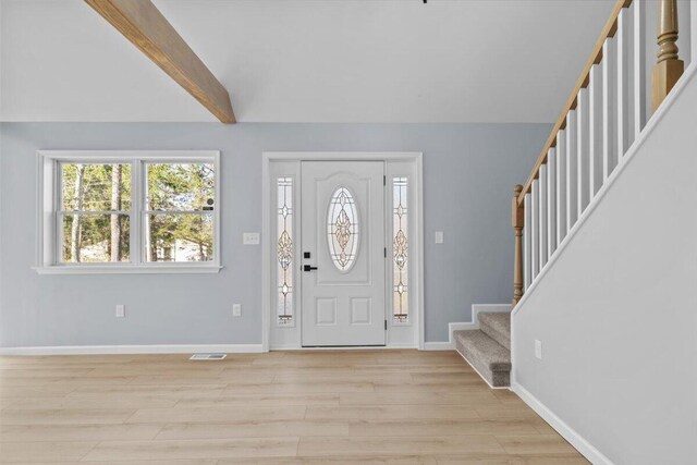 foyer entrance with baseboards, light wood-style flooring, and stairs