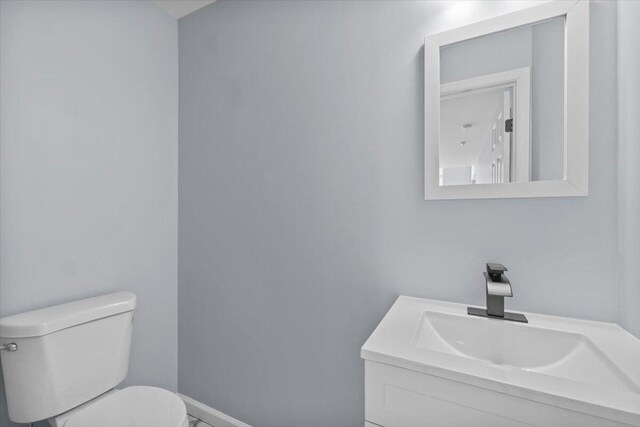 bathroom with baseboards, vanity, and toilet