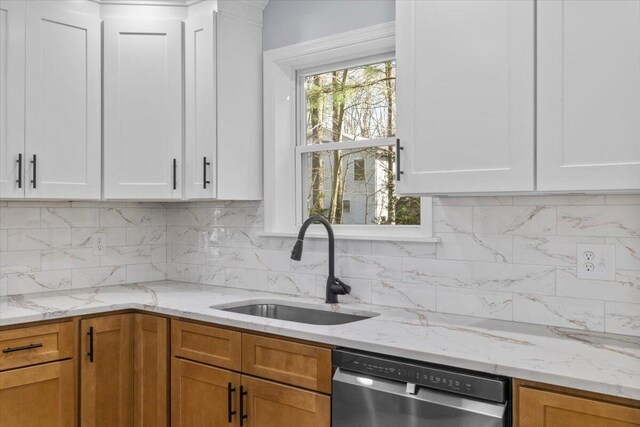 kitchen featuring white cabinetry, light stone counters, a sink, and dishwasher