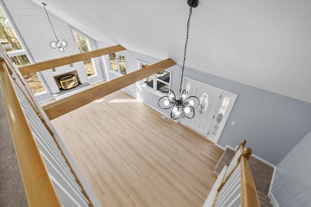 stairs featuring visible vents, wood finished floors, a notable chandelier, and vaulted ceiling