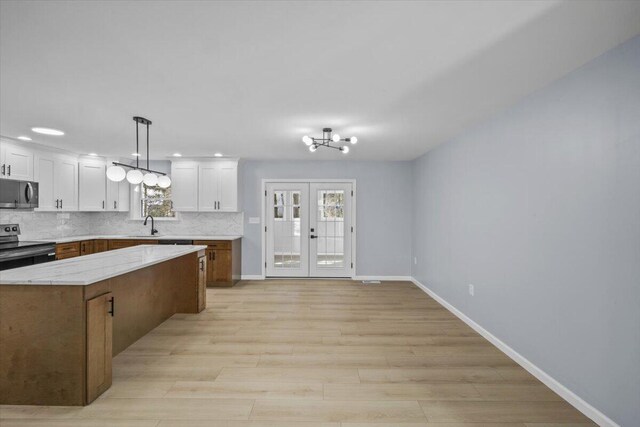 kitchen with appliances with stainless steel finishes, a sink, white cabinetry, baseboards, and decorative backsplash