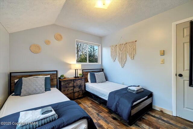 bedroom with lofted ceiling, dark hardwood / wood-style floors, and a textured ceiling