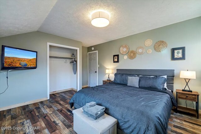 bedroom featuring lofted ceiling, dark wood-type flooring, a closet, and a textured ceiling