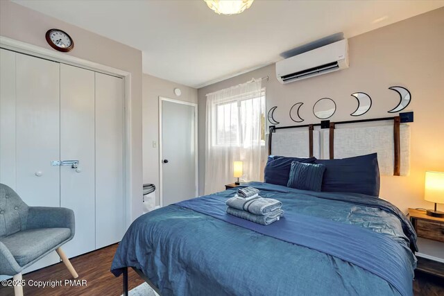 bedroom with a closet, dark wood-type flooring, and an AC wall unit