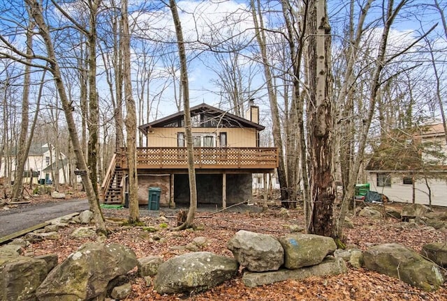 rear view of house featuring stairs, a chimney, and a wooden deck