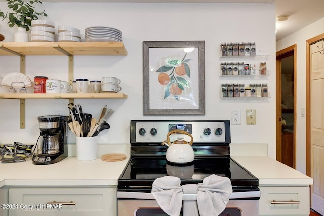 room details featuring stainless steel electric range oven, open shelves, and light countertops