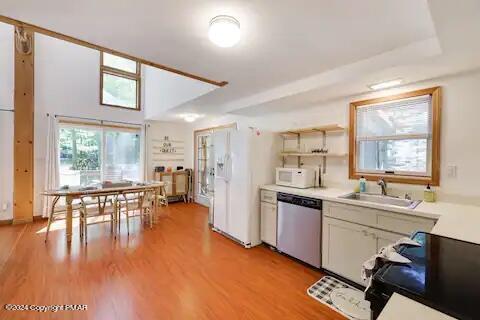 kitchen with white appliances, a sink, light countertops, light wood-type flooring, and open shelves