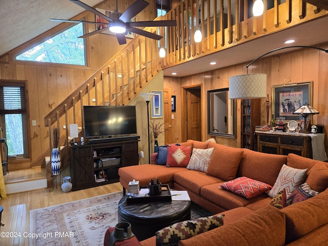 living room featuring wooden walls, high vaulted ceiling, stairs, and wood finished floors