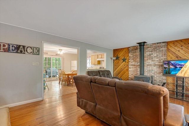 275 Selig Rd, Pocono Lake, PA 18347 - living area with wooden walls, a wood stove, a ceiling fan, an accent wall, and light wood-type flooring