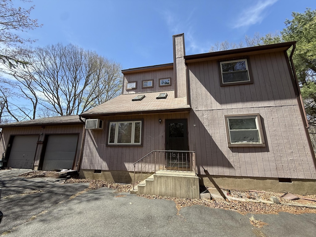 4524 Pine Ridge Dr W, Bushkill, PA 18324 - view of front of property with crawl space, an attached garage, a chimney, and a wall unit AC