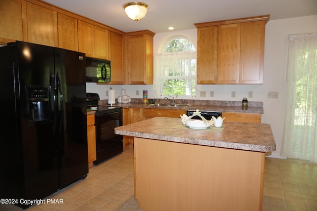 kitchen with light tile patterned flooring, a center island, black appliances, and a sink