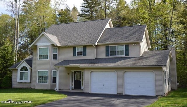 view of front of property with aphalt driveway, a chimney, a front lawn, and roof with shingles